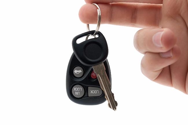 Hand holding a car key fob with keys on a white background
