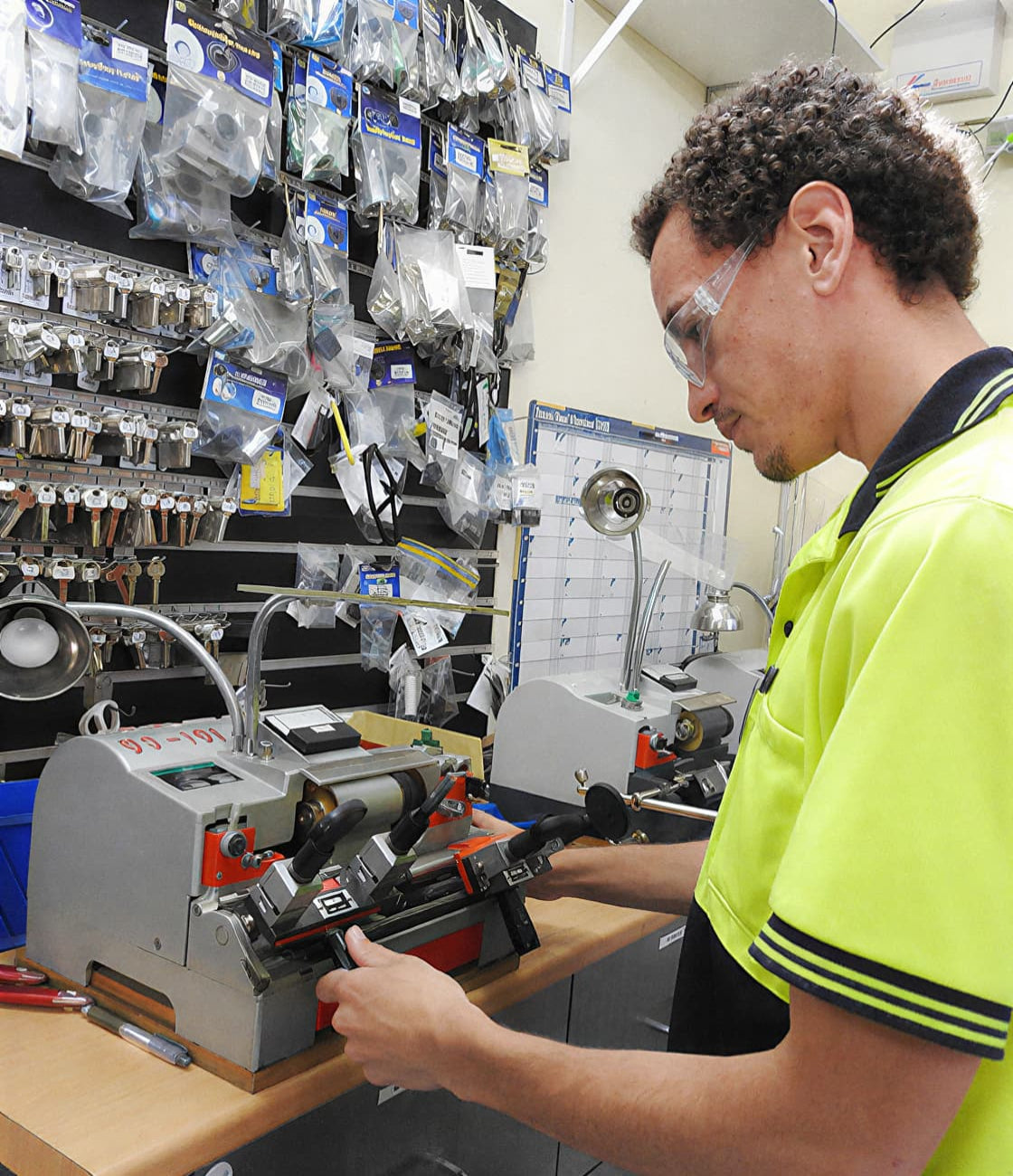 Person using a tool in a workshop setting with tools and equipment on shelves.